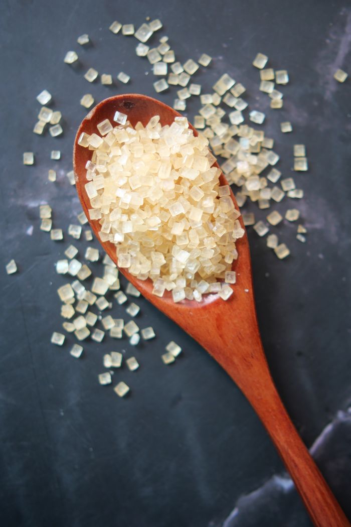 services-02 A detailed view of raw sugar cubes on a wooden spoon over a dark surface.