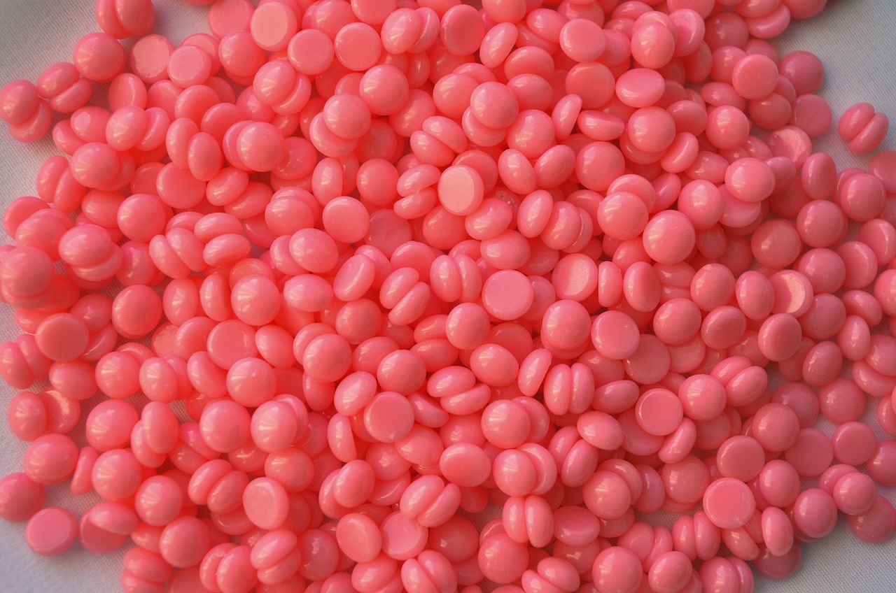 services-02 Close-up of pink wax beads used in cosmetic depilation and hair removal treatments.