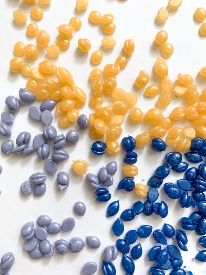 about-01 A vibrant arrangement of colorful wax beads on a white surface, perfect for crafts.